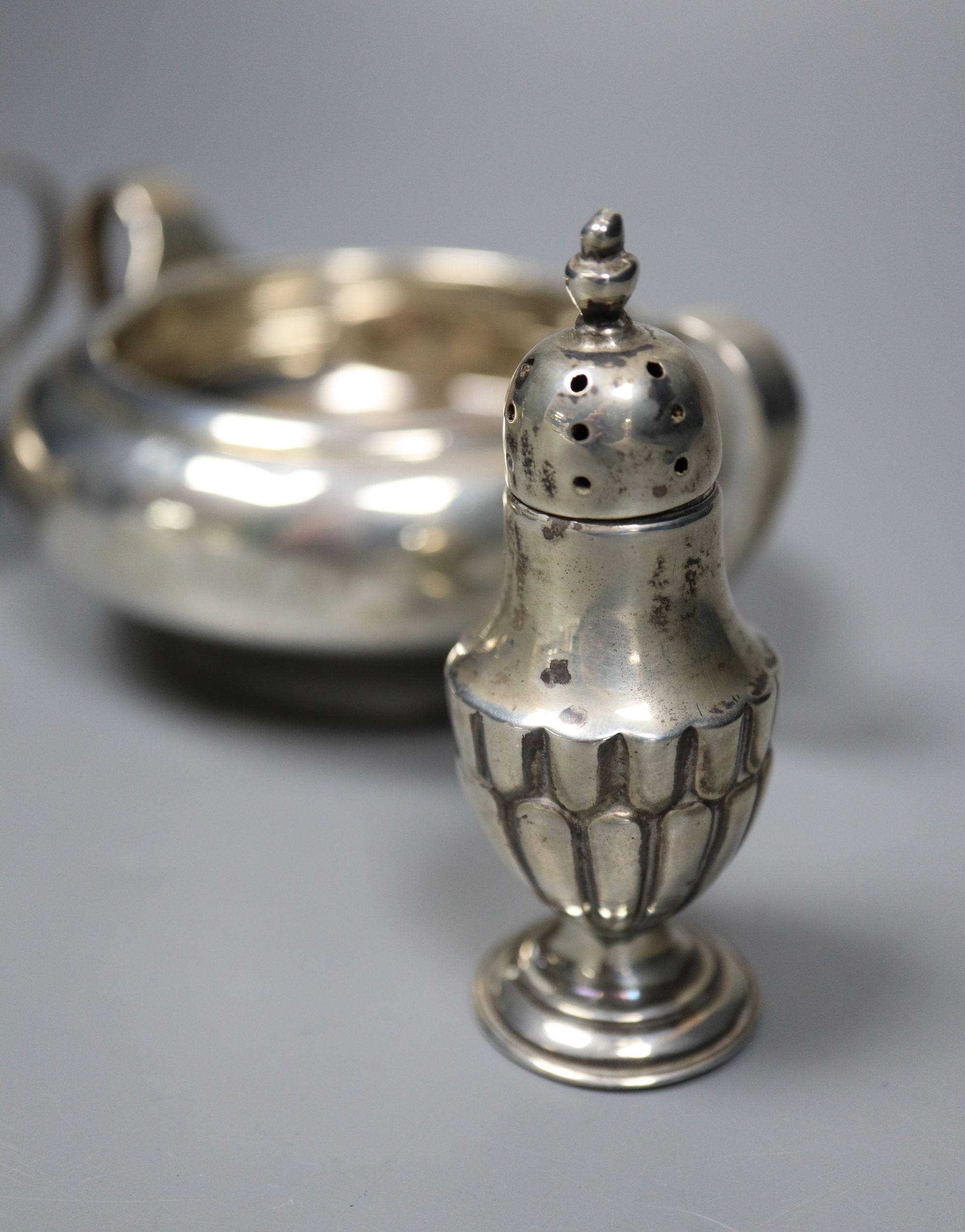 A George V silver sugar bowl and cream jug, London 1935 and a pair of Edwardian silver salt and pepper pots, London 1905,